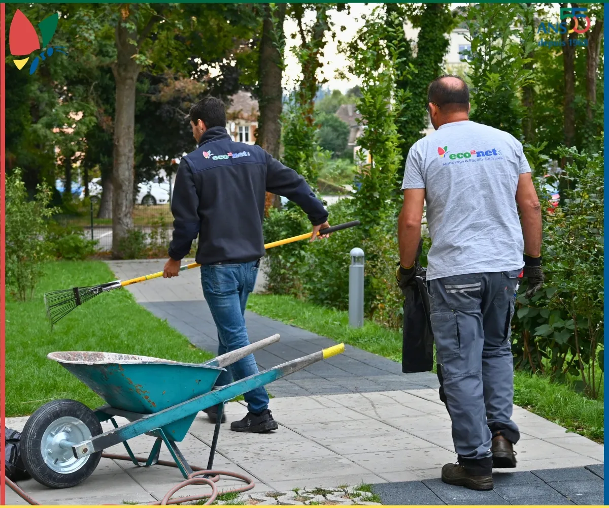 Deux collaborateurs eco2net avec du matériel de jardinage dans un espace vert.