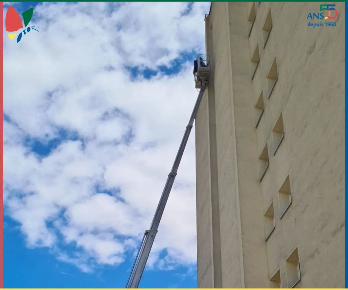 Nacelle élévatrice positionnée le long de la façade d’un bâtiment pour une intervention en hauteur.