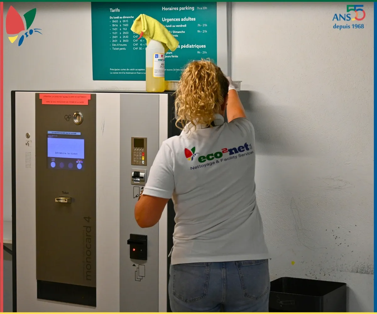 Collaboratrice eco2net nettoyant la zone de la borne de paiement d’un parking.